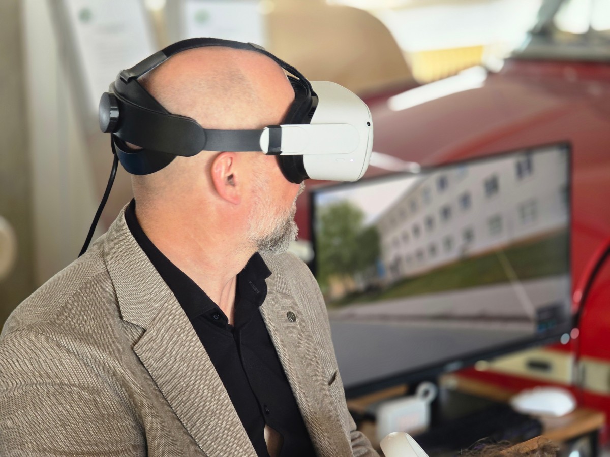 Host ve VR headsetu, na monitoru za ním 3D vizualizace budovy